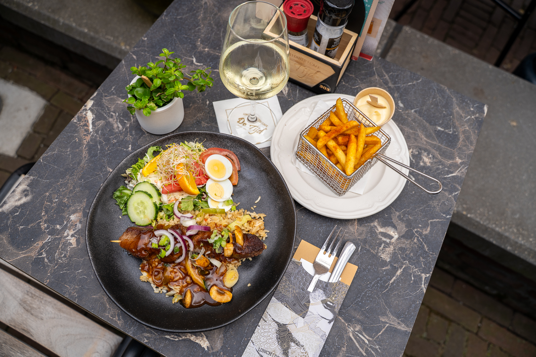 Nasi bord met friet en witte wijn op het terras